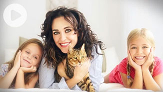 A woman and two girls smiling with a cat.