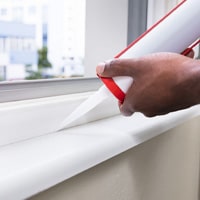 A man caulking a window.