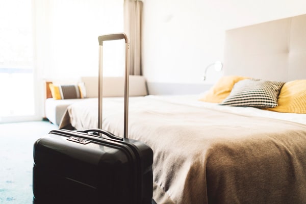 A suitcase in front of a bed.