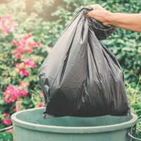 A trashbag being pulled from a trash can.