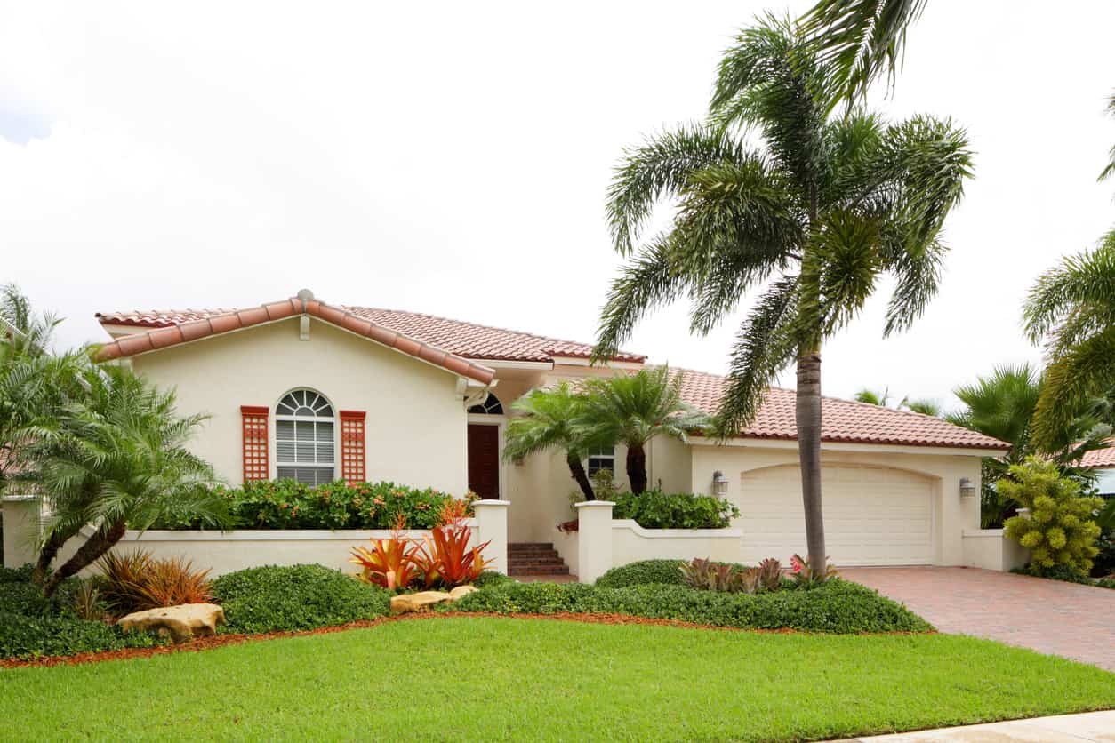 Exterior of a Florida home with a green lawn and palm trees.