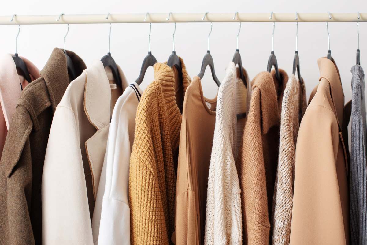 Shirts, jackets, and other clothes hanging in a closet.