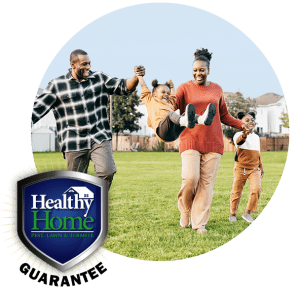 A family playing in the yard with the Healthy Home Guarantee badge.