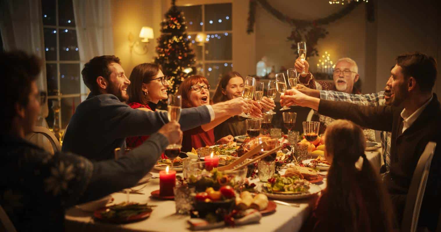 A family gathers by a table and toasts with champagne during Christmas