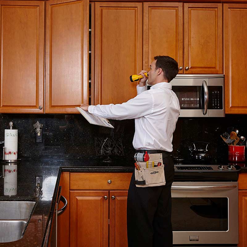 A technician inspecting kitchen cabinets.
